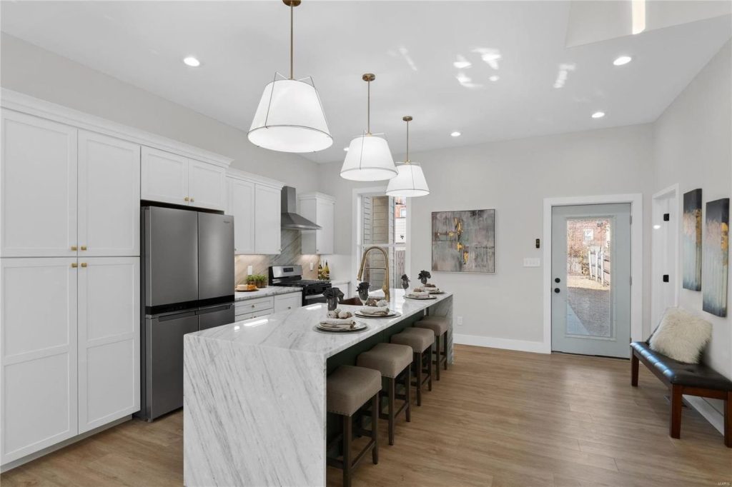 Kitchen with marble island, stools and stainless refrigerator