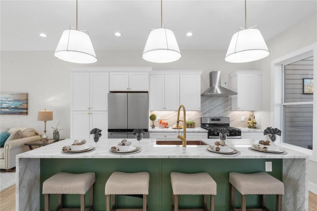 Kitchen with green island, marble countertops and gold faucet