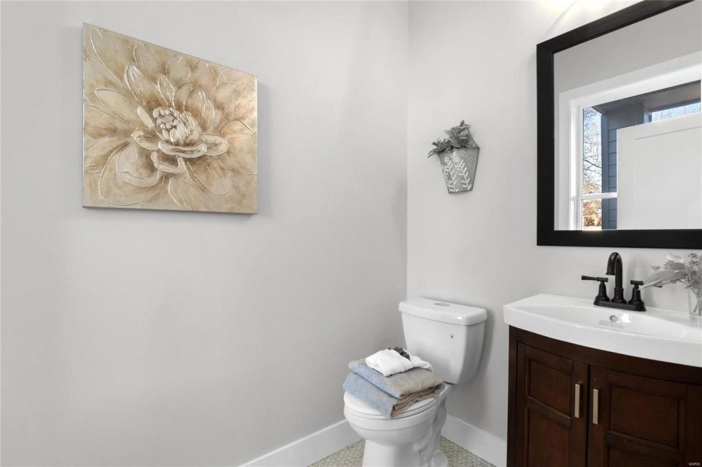 Powder room with dark vanity and framed mirror