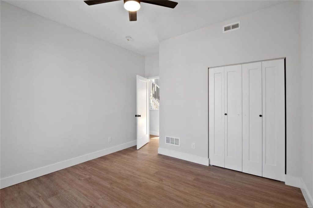 Empty bedroom with ceiling fan and closet doors