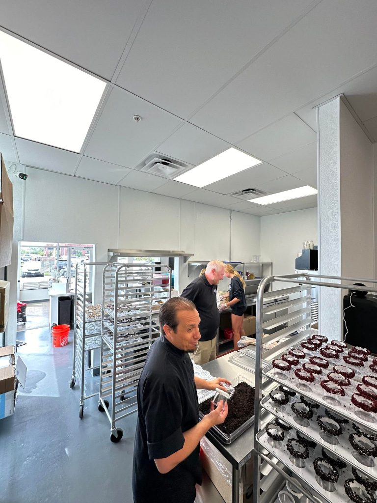 Staff decorating desserts on bakery racks