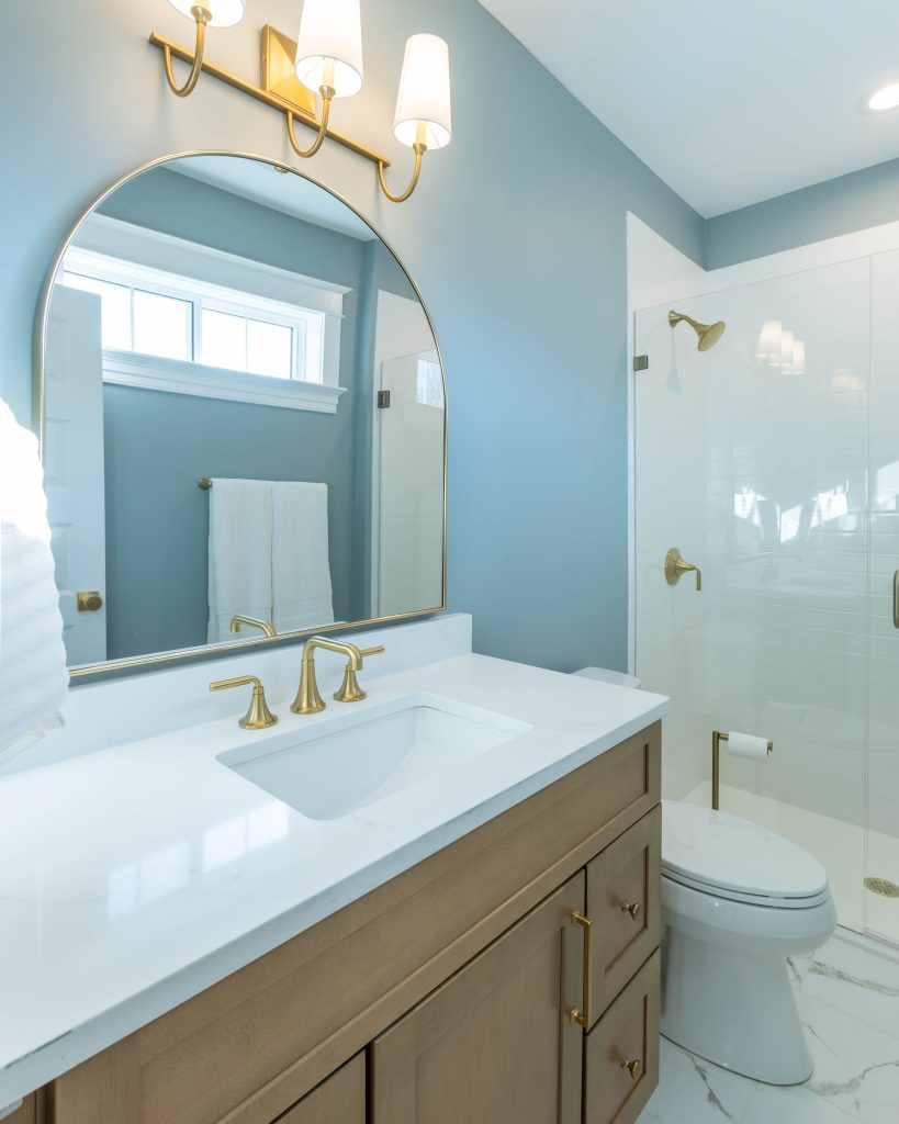 Blue bathroom with arched mirror and glass shower