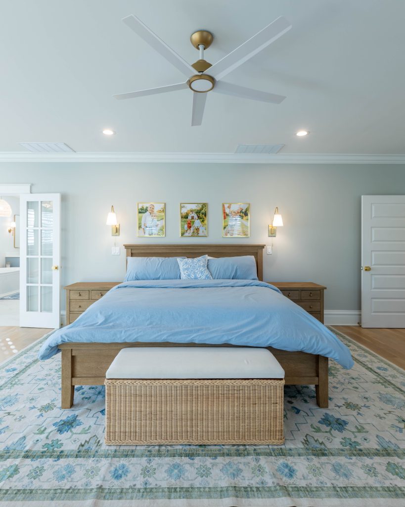Bed framed by sconces with a wicker storage bench