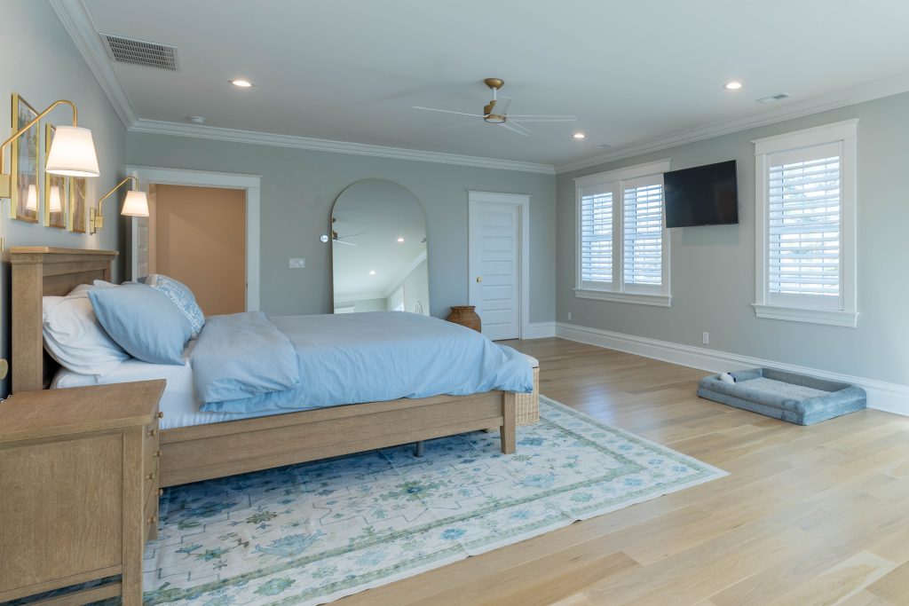 Primary bedroom with arched floor mirror and oak floors