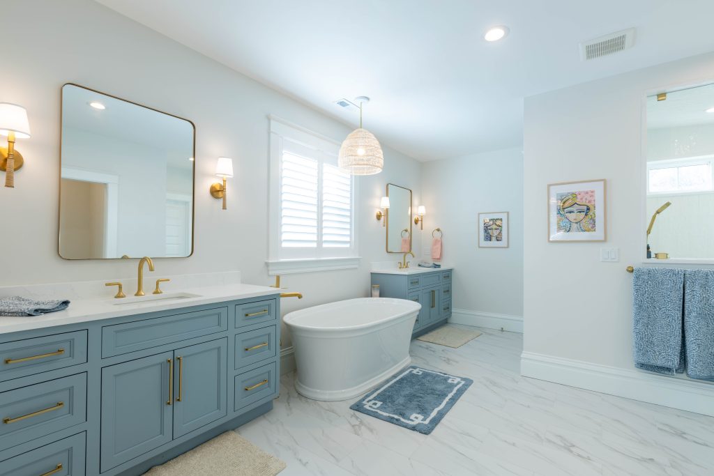 Primary bathroom with twin blue vanities and freestanding tub