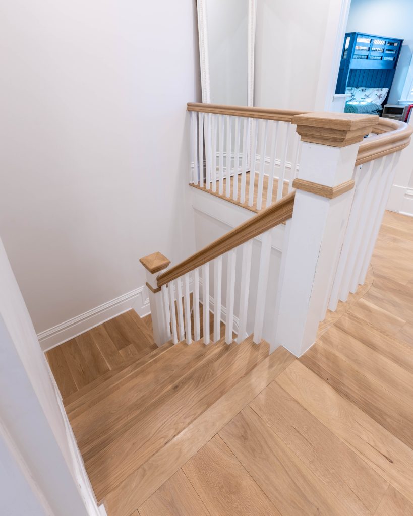 Oak stair rail and white balusters at the landing
