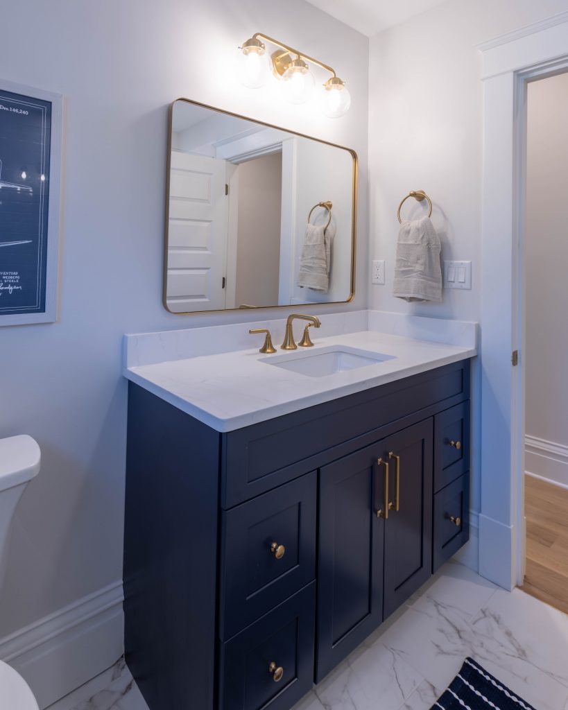 Navy vanity with brass faucet and framed mirror