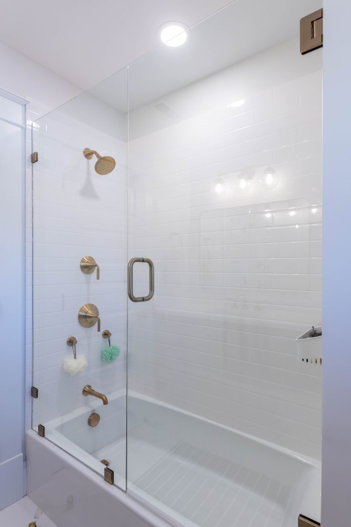 Tiled tub and shower with glass panel and brass fittings
