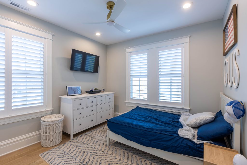 Bedroom with twin bed, dresser and wall-mounted TV