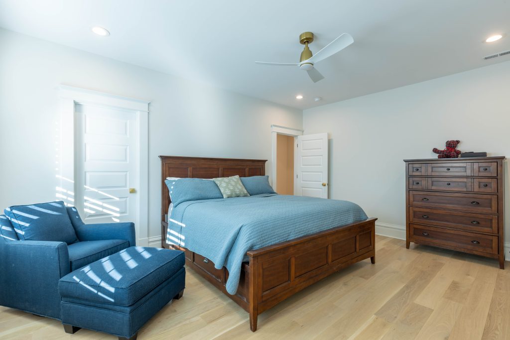 Bedroom with armchair, ottoman and tall dresser