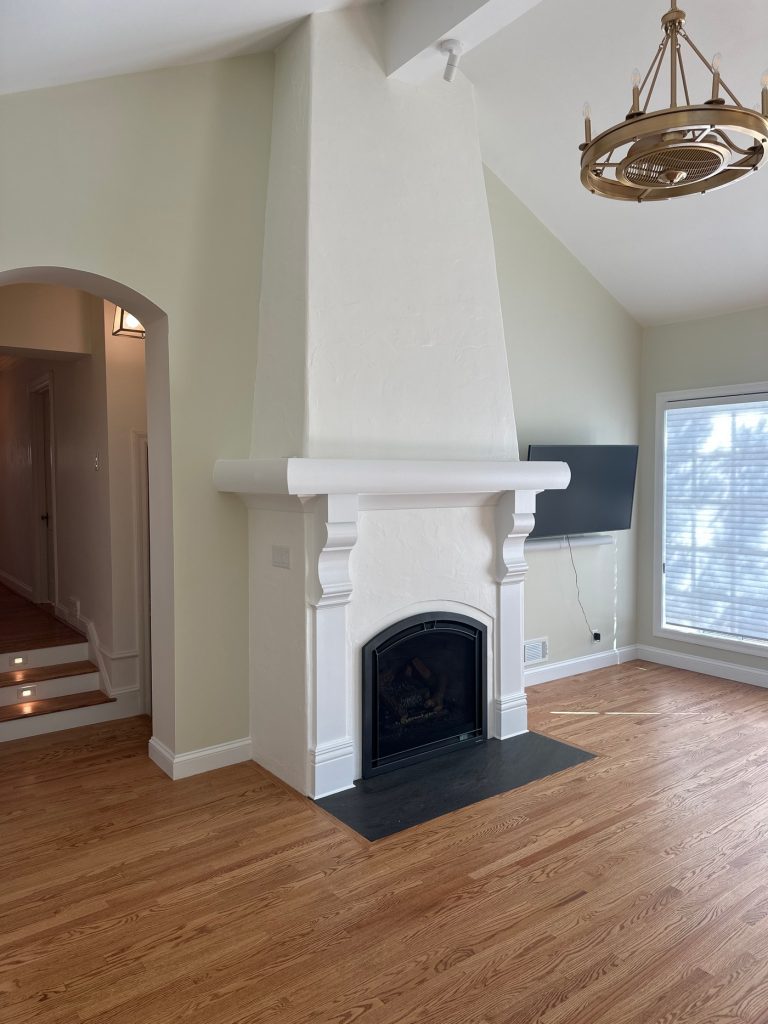Plaster fireplace with arched firebox and stone mantel