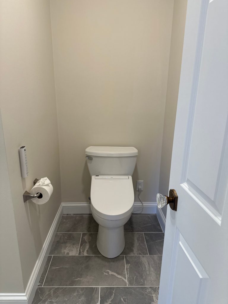 Water closet with bidet seat and stone tile floor