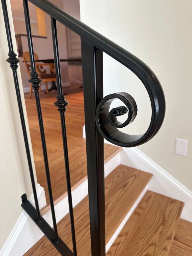 Scrolled iron handrail at the top of the stairs