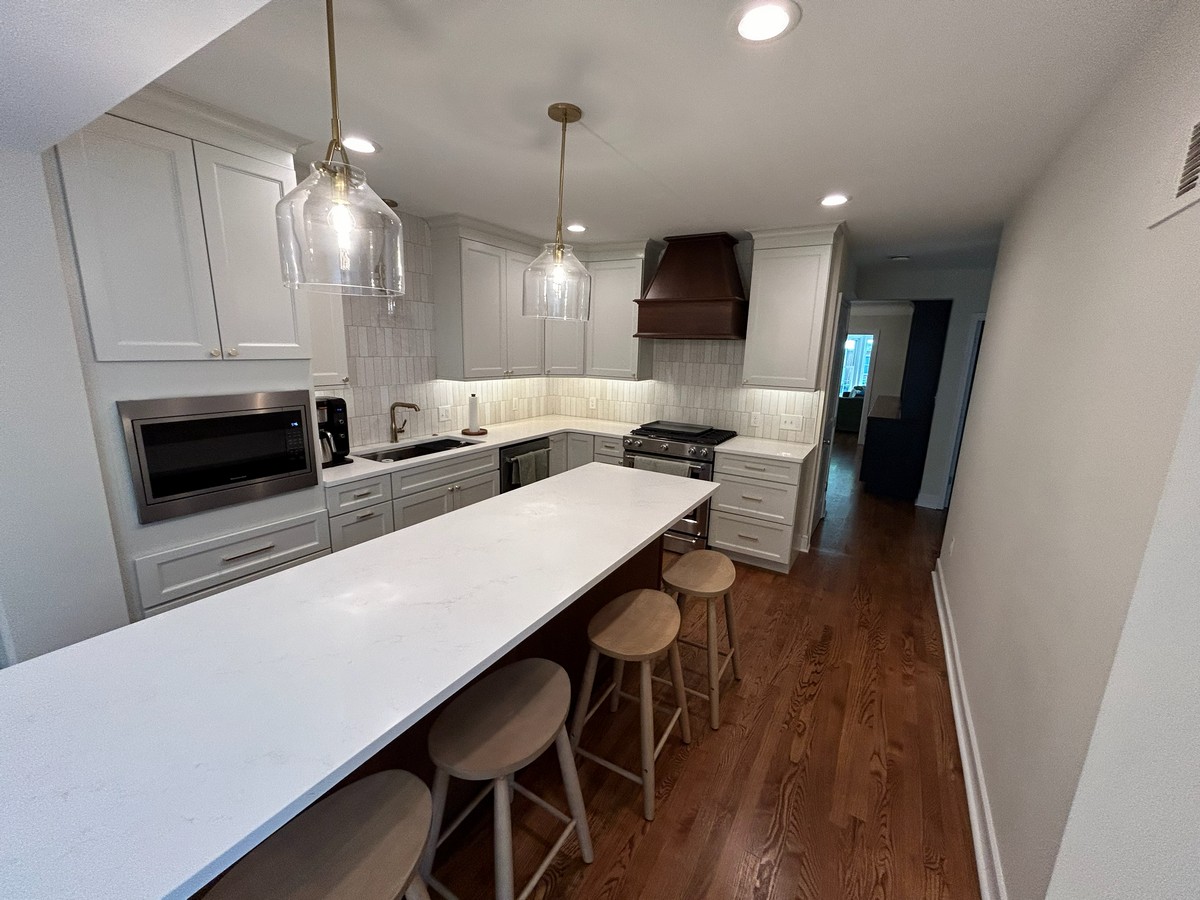 Kitchen peninsula with glass pendants and copper hood