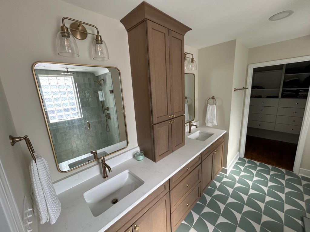 Double vanity with brass sconces and walk-in closet beyond