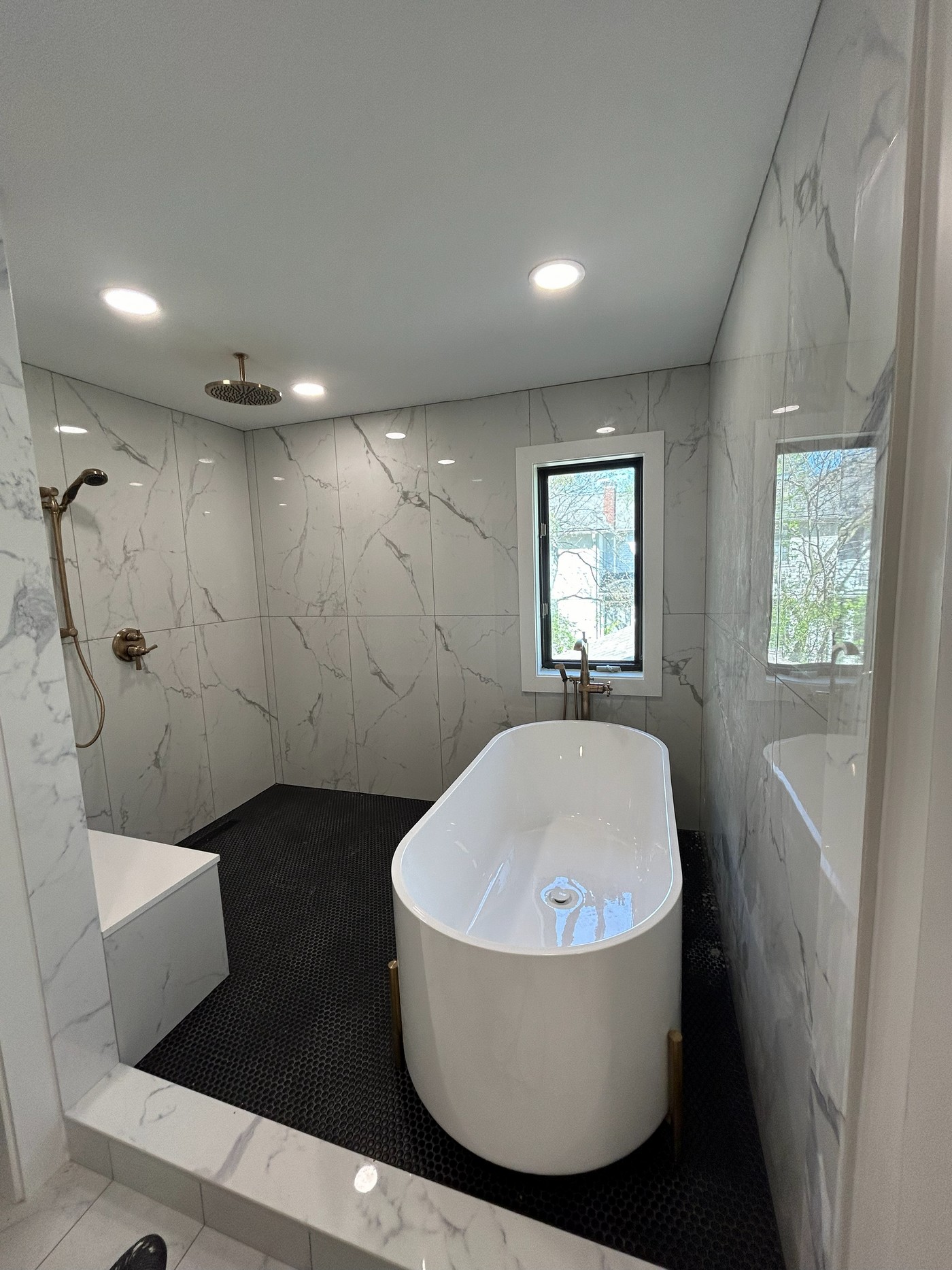 Wet room with freestanding tub and marble tile