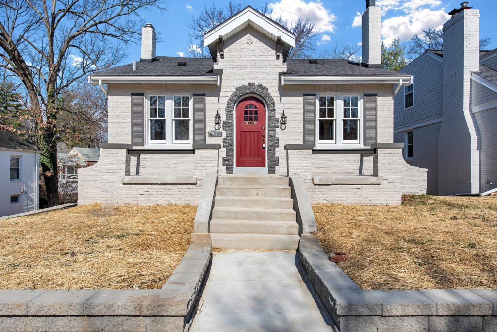 Painted brick bungalow with red arched front door