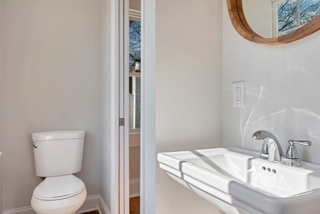 Powder room with wall-mounted sink and round mirror