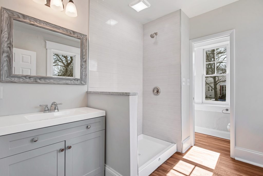 Bathroom with gray vanity and tiled corner shower
