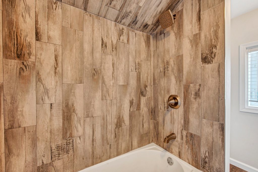 Tub surround in wood-look tile with brass fittings