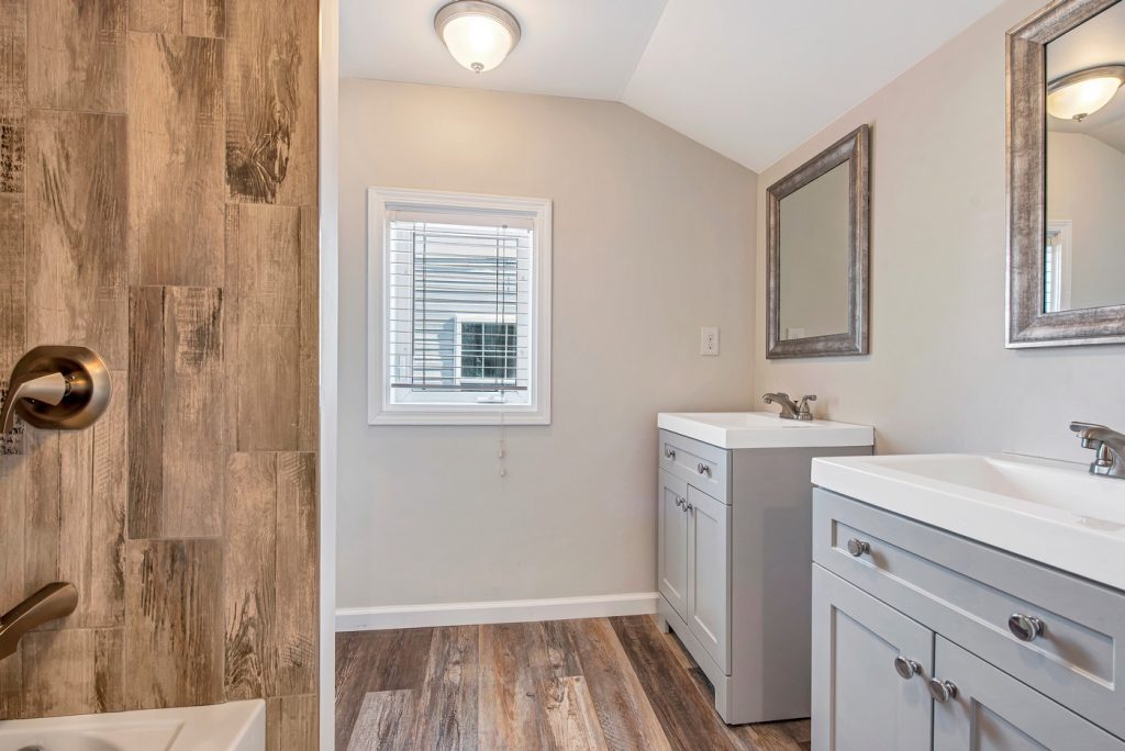 Bathroom with twin gray vanities and wood-look tile