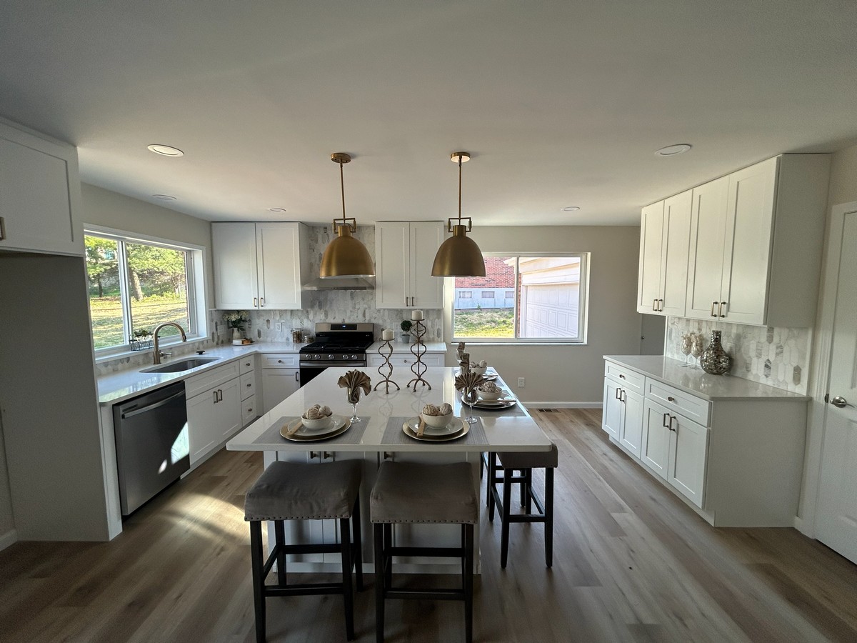 White kitchen with island seating and brass pendant lights