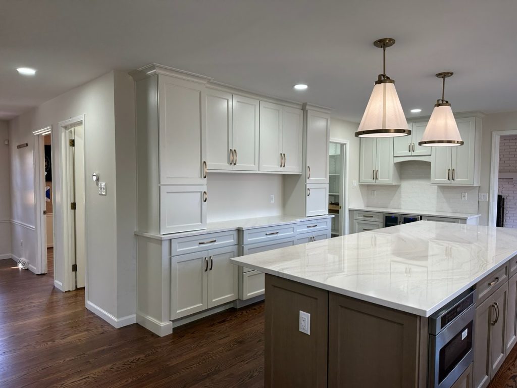 Remodeled kitchen with marble island and brass pendant lights