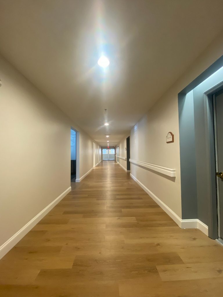 Resident corridor with wall handrail and teal doorway