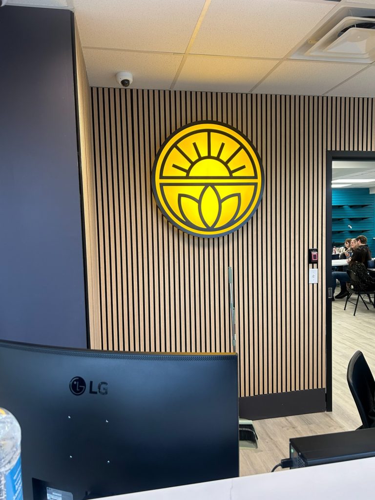 Illuminated sunburst logo on a slatted wood wall
