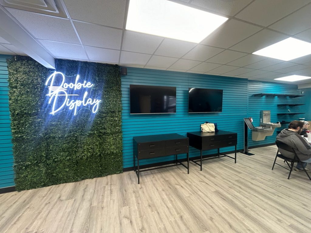 Hedge feature wall with neon sign and wall-mounted screens