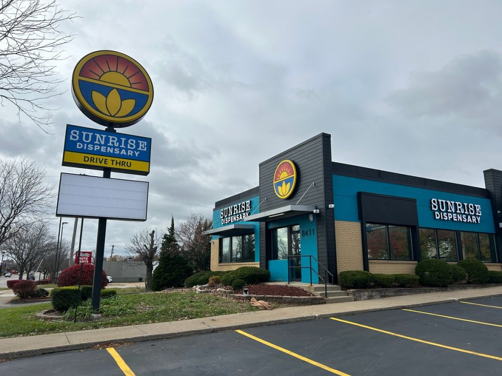 Dispensary exterior with illuminated pylon sign and drive-thru