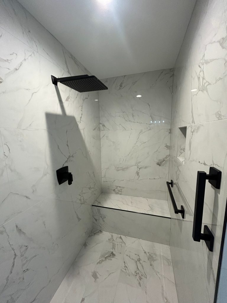 Marble-tiled shower with recessed niche and black fittings