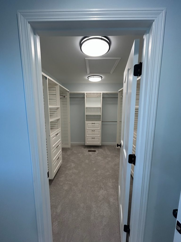 Walk-in closet with white shelving seen from the doorway
