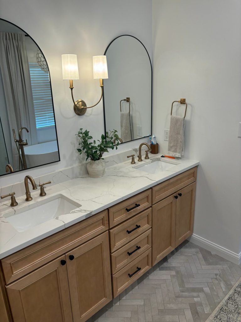 Double vanity with arched mirrors and brass sconce