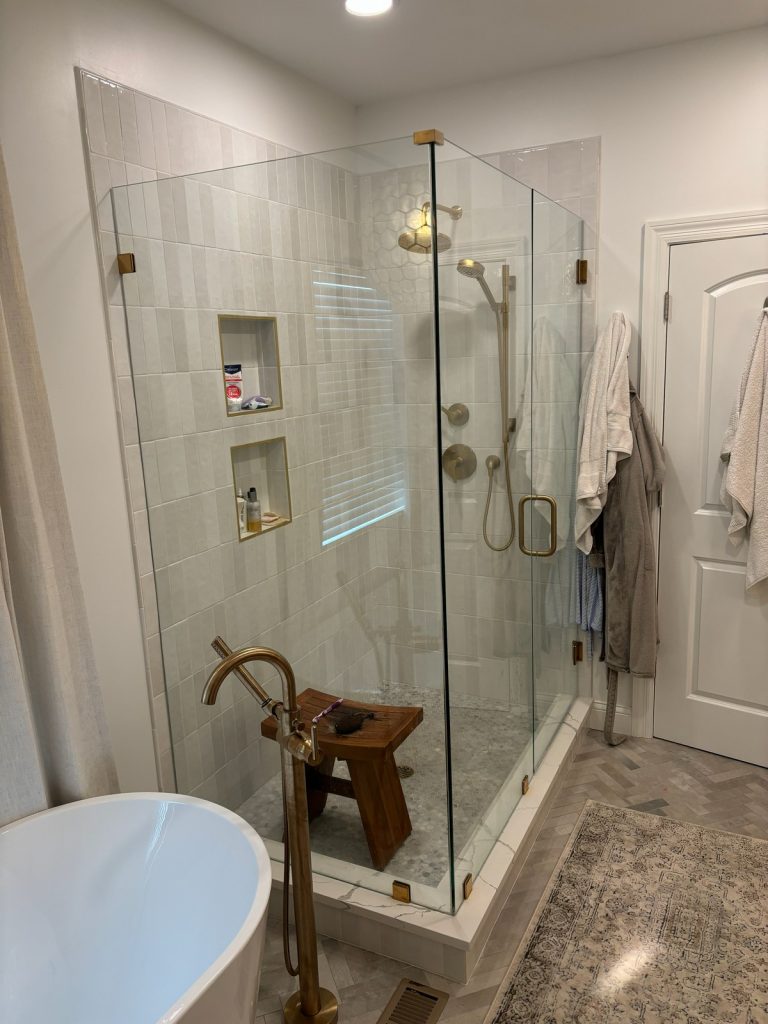 Glass shower with teak bench and tiled niches