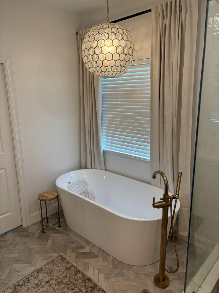 Soaking tub framed by linen curtains and pendant