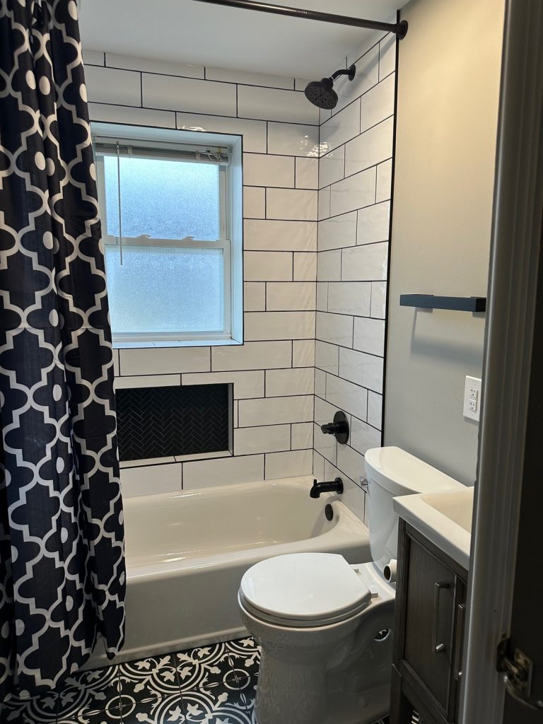 Bathroom with subway tiled tub and patterned floor