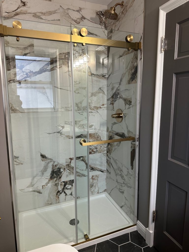 Marble-tiled shower with brass sliding glass door