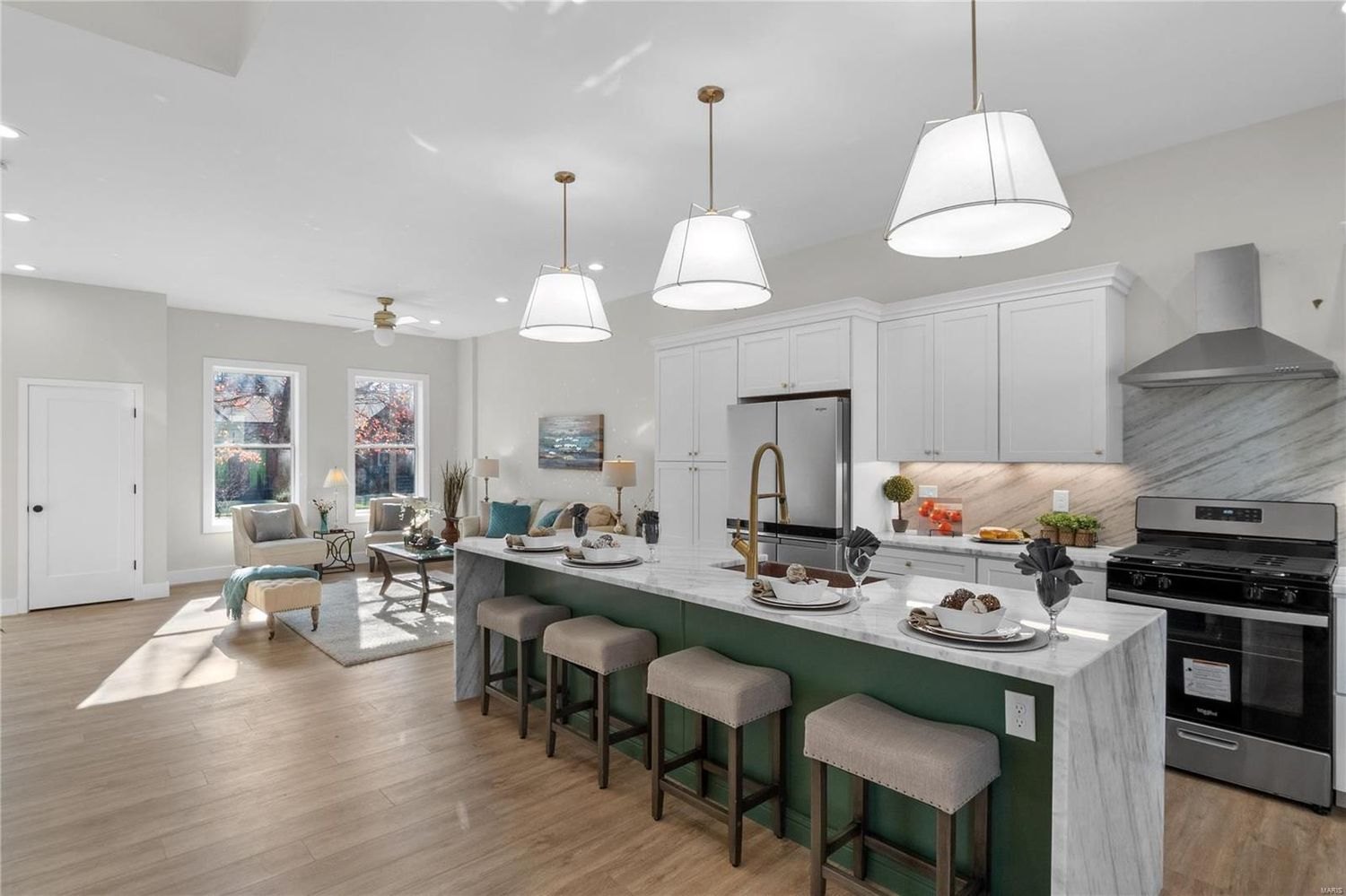 Open plan kitchen with a green island and bar seating in an expanded home