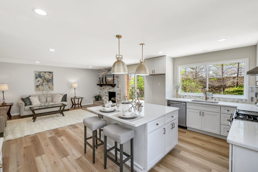 Kitchen with white island, pendant lights and living room beyond