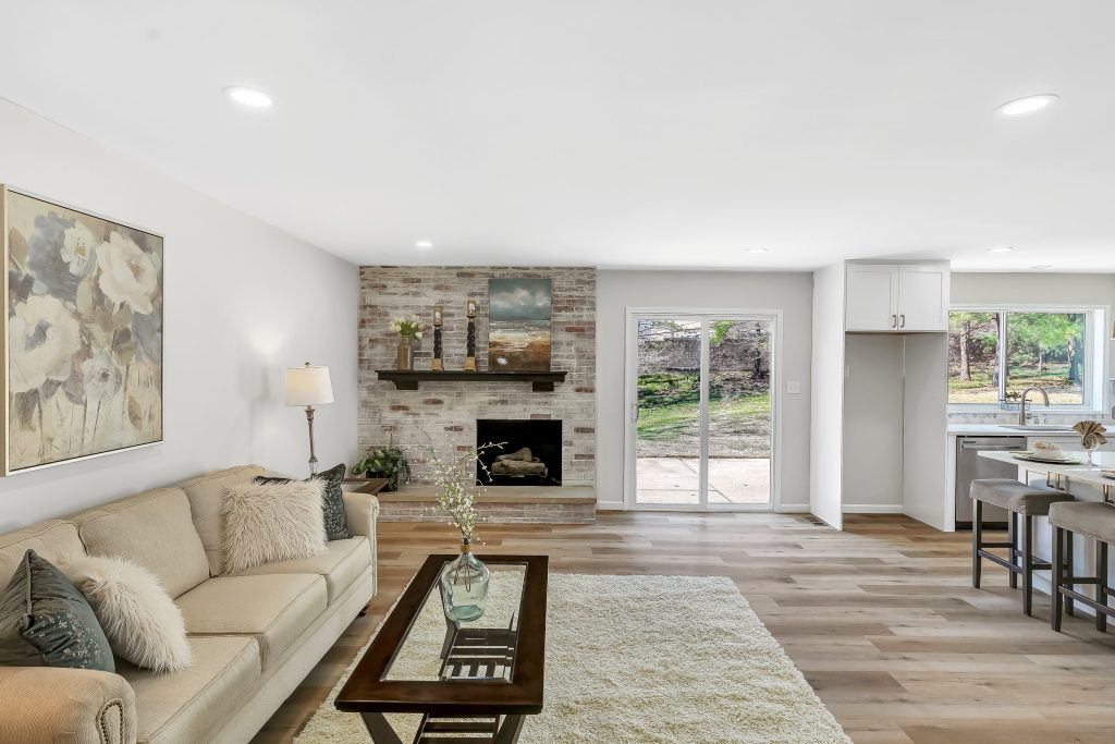 Living room with stone fireplace and kitchen beyond