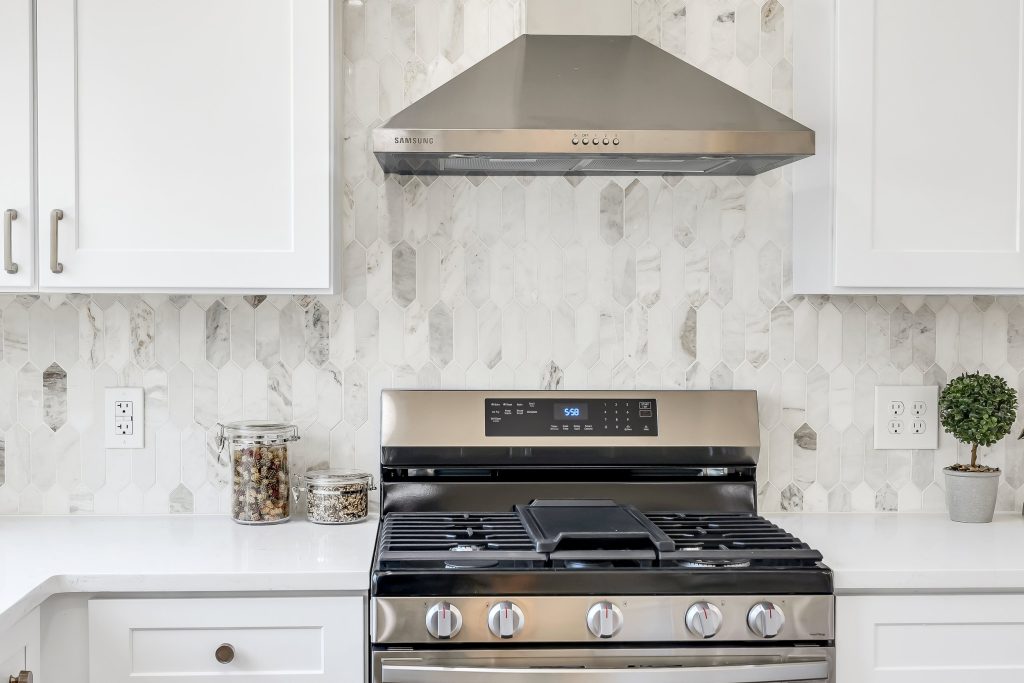 Range with stainless hood and marble backsplash
