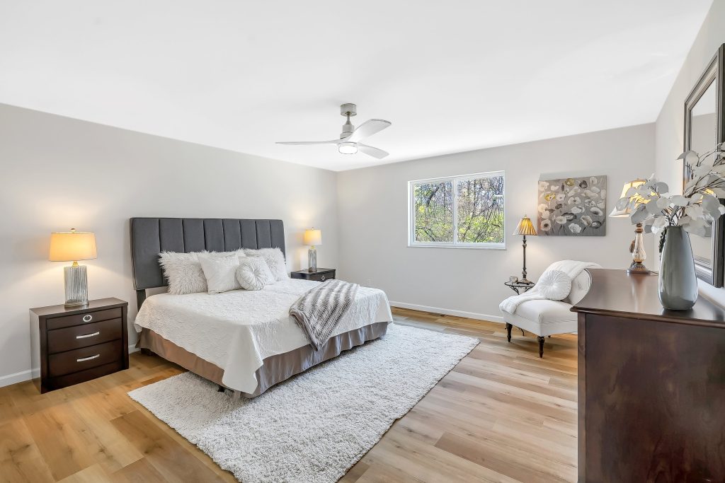 Primary bedroom with gray headboard and ceiling fan