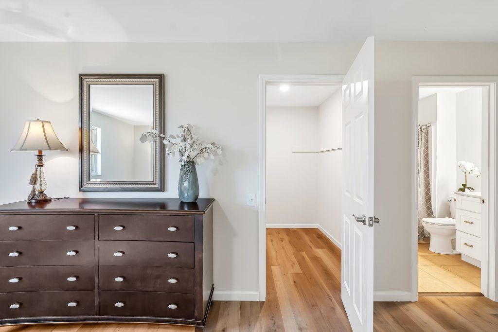 Bedroom with dresser, mirror and en suite beyond