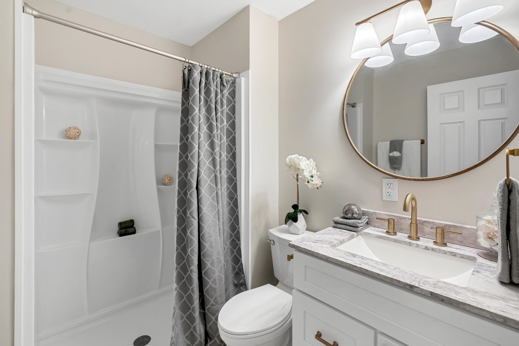 Bathroom with white vanity, round mirror and tub