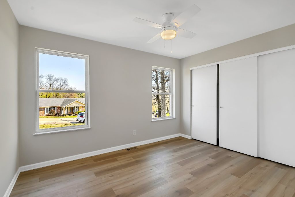 Empty bedroom with ceiling fan and closet doors