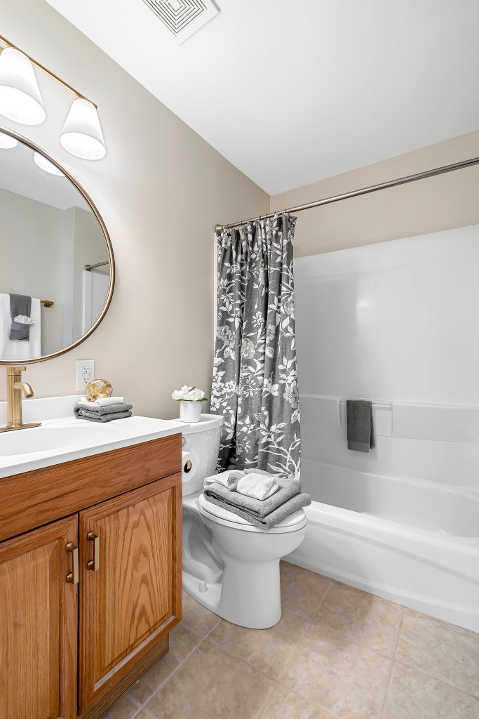 Bathroom with oak vanity, round mirror and tub