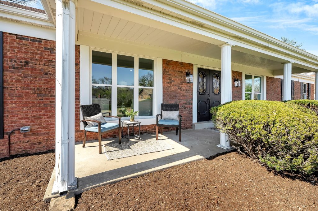 Covered patio with wicker seating and brick wall