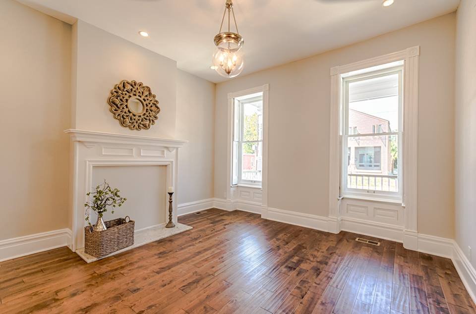 Living room with white fireplace mantel and tall double windows