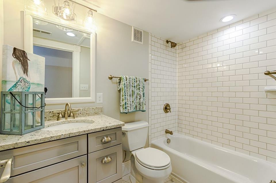 Bathroom with gray vanity, framed mirror and subway tile tub surround
